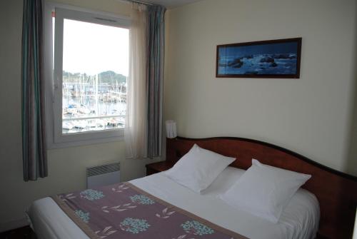 Bett in einem Hotelzimmer mit Fenster in der Unterkunft Hôtel Le Goëlo - Port de Paimpol in Paimpol