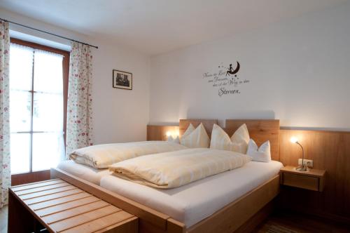 a bedroom with a large white bed with a window at Plenkhof in Ruhpolding