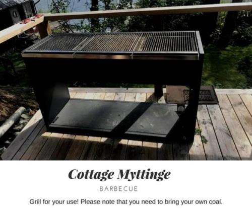 a black picnic table sitting on a wooden deck at Fishermans cabin in Myttinge