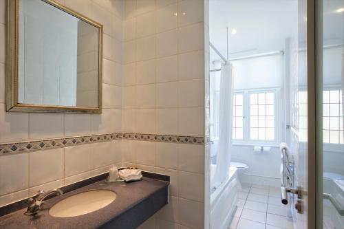 a bathroom with a sink and a mirror and a tub at Bournemouth East Cliff Hotel, Sure Hotel Collection by BW in Bournemouth