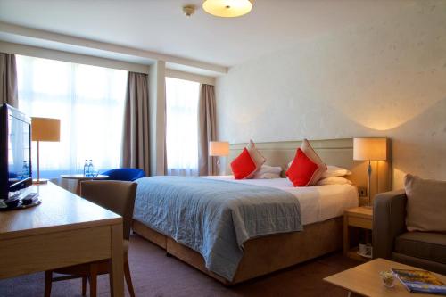 a hotel room with a large bed with red pillows at Bournemouth East Cliff Hotel, Sure Hotel Collection by BW in Bournemouth