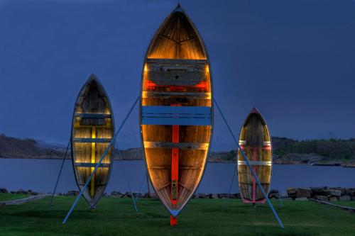 three boats sitting on the grass near a body of water at Hotel Wassilioff - Unike Hoteller in Stavern