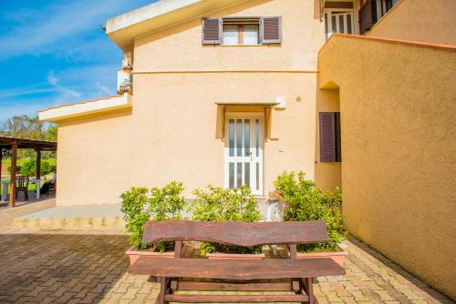 a wooden bench sitting in front of a building at Bonsai B&B Alghero in Santa Maria la Palma