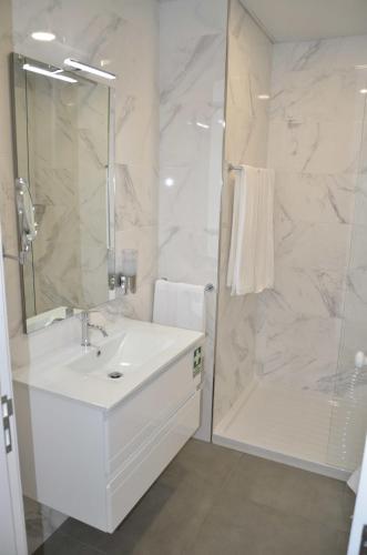 a white bathroom with a sink and a shower at Edificio Charles 104 in Funchal