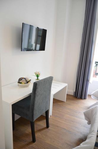 a white desk with a chair and a television on a wall at Edificio Charles 104 in Funchal