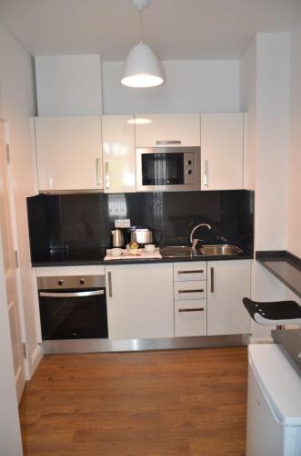 a kitchen with white cabinets and a sink and a microwave at Edificio Charles 104 in Funchal