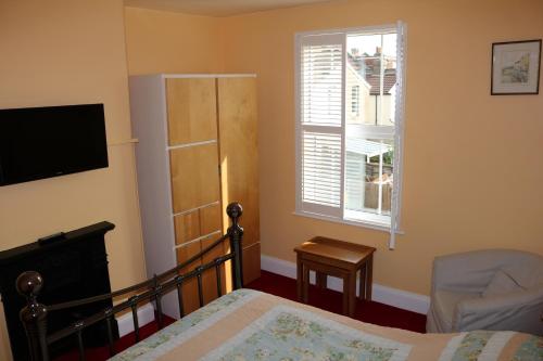 a bedroom with a bed and a chair and a window at Norfolk Guest House in Bristol