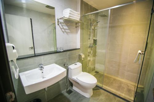 a bathroom with a toilet and a sink and a shower at INDRA HOTEL - BOUTIQUE SUITES in Ipoh