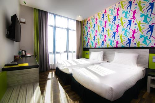 two beds in a hotel room with a painting on the wall at INDRA HOTEL - BOUTIQUE SUITES in Ipoh