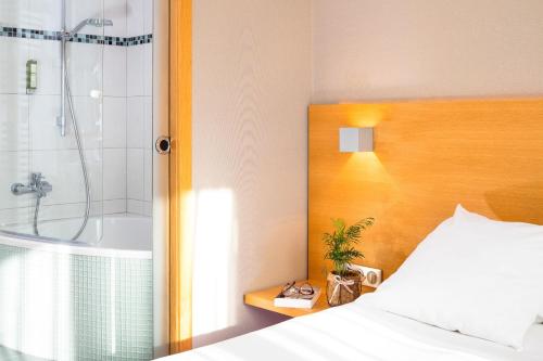 a bedroom with a bed and a shower and a tub at Auberge Sundgovienne in Carspach