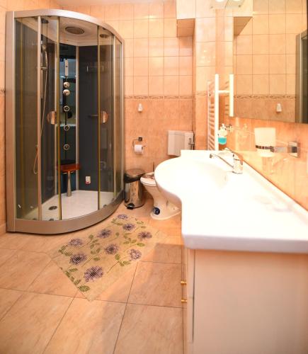 a bathroom with a shower and two sinks and a toilet at Apartament TRIDENT 2 in Haţeg