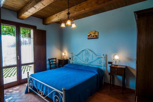 a bedroom with a blue bed and a window at Country House Il Tiglio in Mergo