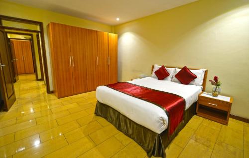 a hotel room with a large bed with red pillows at Bukoto Heights Apartments in Kampala