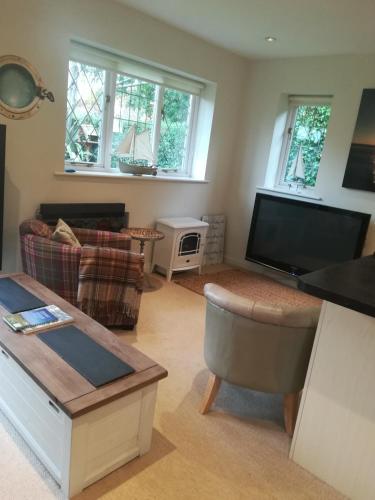 a living room with a couch and a flat screen tv at The Gate Cottage in West Itchenor