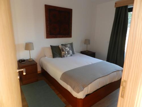 a bedroom with a bed with two lamps and a window at Vale Dos Milhafres in Angra do Heroísmo