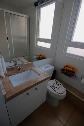 a bathroom with a sink and a toilet and a window at Sector Enjoy Premium Frente al Mar in Coquimbo