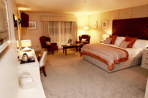 a hotel room with a bed and a desk and chairs at Mellon Country Inn Hotel in Omagh