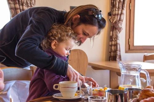 Una mujer sosteniendo a una niña pequeña en una mesa en Hotel les Flocons, en Le Grand-Bornand