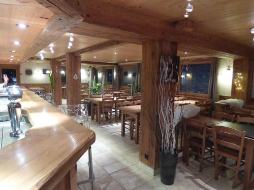 ル・グラン・ボルナンにあるHotel les Floconsのテーブルと椅子が備わるウッドフロアのレストランを併設しています。