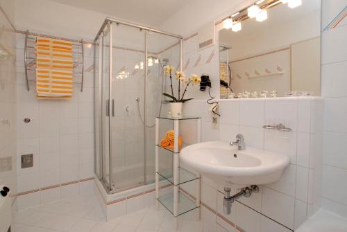biała łazienka z prysznicem i umywalką w obiekcie Dachstein West Hotel GmbH-Kirchenwirt Russbach w mieście Rußbach am Paß Gschütt