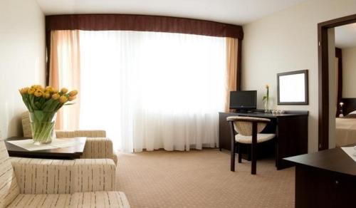 a hotel room with a desk and a living room at Pensjonat Boss z Restauracją 50 metrów od Morza! in Dziwnów