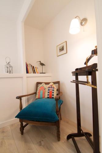Cette chambre dispose d'une chaise avec un oreiller bleu. dans l'établissement Villa Prat Bras - Appartements, à Clohars-Carnoët
