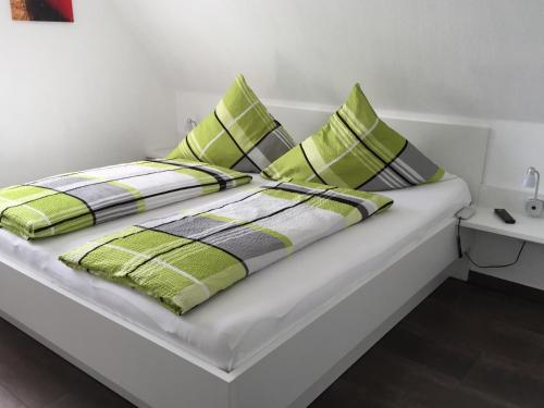 a bed with green and white pillows on it at Skippersin2 in Greetsiel