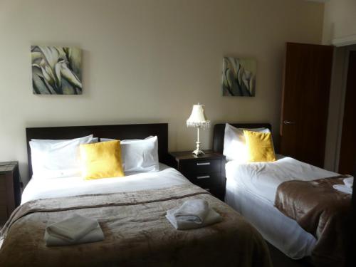 a hotel room with two beds with yellow pillows at The Courtyard Apartments in Carrick on Shannon