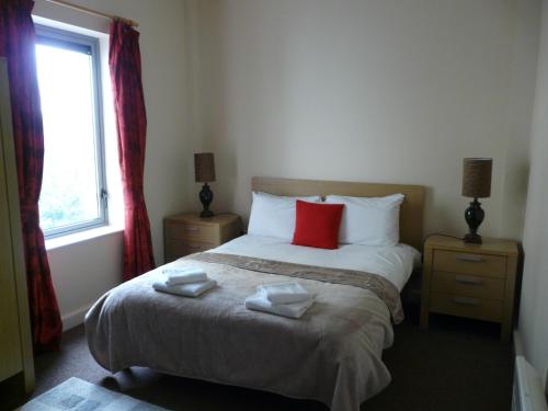a bedroom with a bed with red pillows and a window at The Courtyard Apartments in Carrick on Shannon