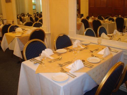 a dining room with a table with silverware and a mirror at The Hydro Hotel in Douglas