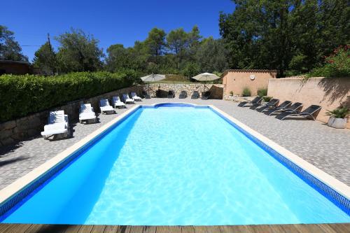 a blue swimming pool with lounge chairs and a house at Le Mas du Vieux Chene in Saint-Paul-en-Forêt