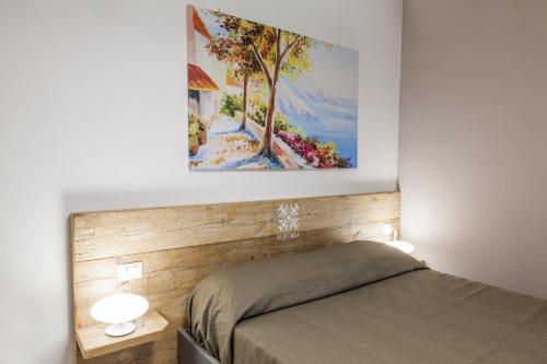 ナポリにあるEuforia Napoli - Tre Sedi - Three Locationsのベッドルーム1室(ベッド1台付)が備わります。壁には絵画が飾られています。
