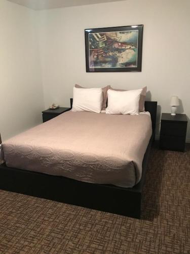 a bedroom with a bed with two night stands and two tables at Grizzly Motel in Swan Hills