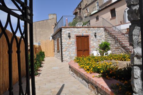 a stone building with a red door and some flowers at Villetta in Centro Storico in Caccamo