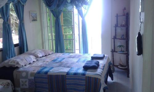 a bedroom with a bed with blue curtains and a window at Posada Sweet Anashly in Providencia