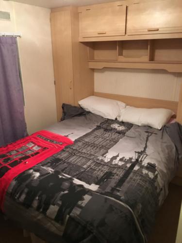 a bedroom with a bed with a black and white blanket at 4 bedroom caravan ingoldmells skegness in Ingoldmells