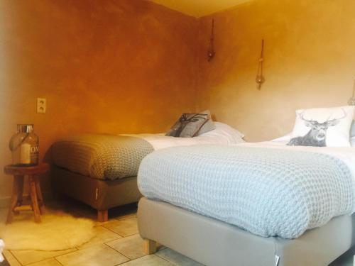 a bedroom with two beds and a ottoman at La Balade du Ricochet in Tenneville