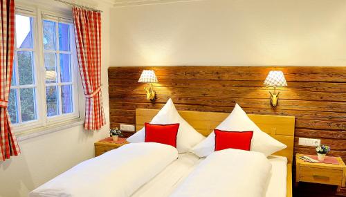 two beds in a hotel room with red and white pillows at Hotel-Gasthof Adler in Lindau
