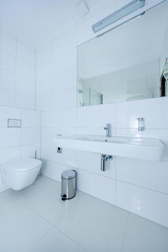 a white bathroom with a sink and a toilet at Hotel Active in Szczecinek