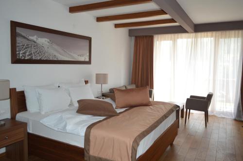 a bedroom with a bed and a chair and a window at Apartments B&P in Jahorina