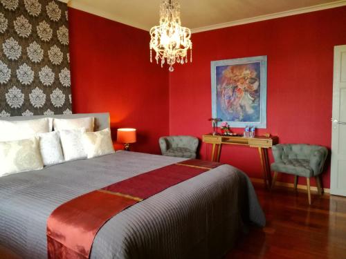 a red bedroom with a bed and a chandelier at B&B Frangipani Bali in Waregem