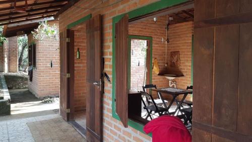 a person is standing in the doorway of a brick house at Beco das Garrafas in Vale do Capao