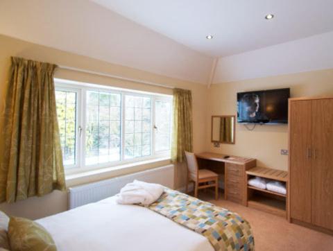 a bedroom with a bed and a desk and a window at Clover Spa and Hotel in Birmingham