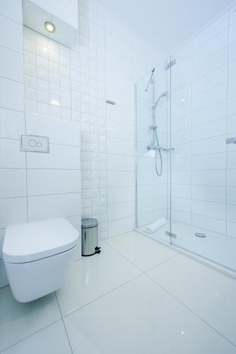 a white bathroom with a shower and a toilet at Hotel Active in Szczecinek