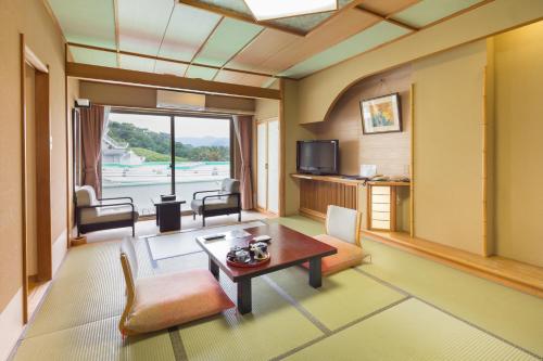 a living room with a table and a tv at Dogashima Onsen Hotel in Nishiizu