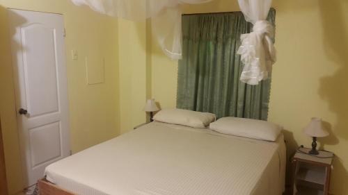 una camera da letto con un letto bianco con una finestra di Lillibets a Castara