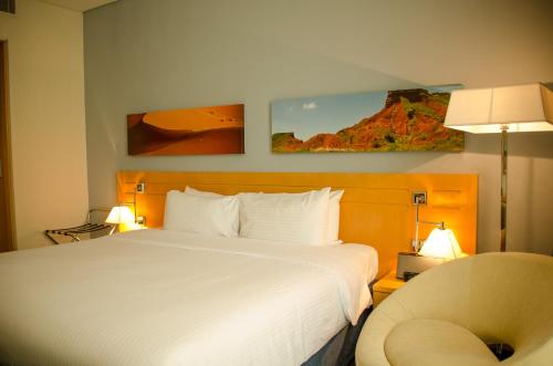 a hotel room with a bed and a chair at City Seasons Hotel & Suites Muscat in Muscat