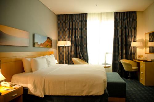 a hotel room with a bed and a window at City Seasons Hotel & Suites Muscat in Muscat