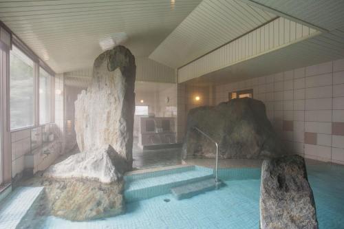 a room with a swimming pool with large rocks in it at Hotel Heian in Fuefuki