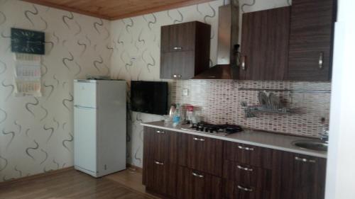 a kitchen with wooden cabinets and a white refrigerator at Gabala Homes Musa in Gabala